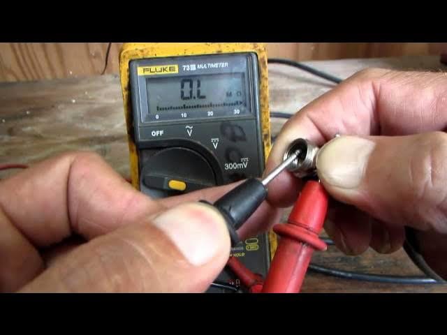 Close-up of hands using a digital multimeter to test the center conductor of a coaxial cable