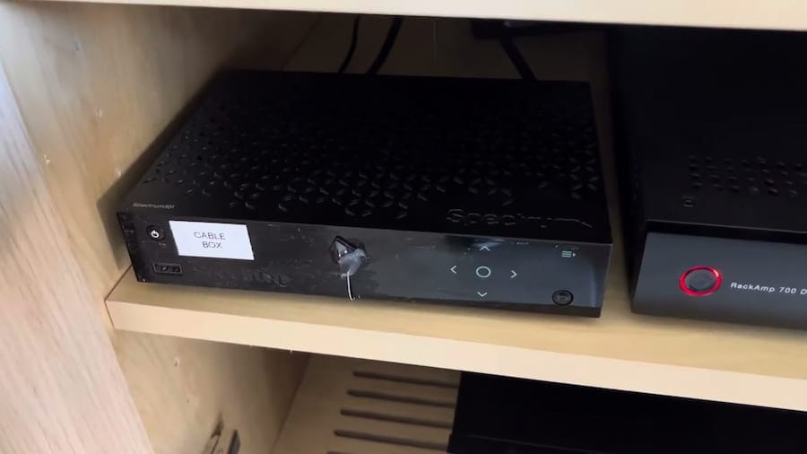 Black Spectrum cable box sitting on a wooden shelf with power and connection ports visible