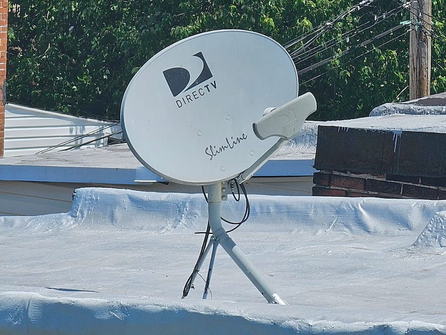 Clean DirecTV satellite dish properly mounted on a rooftop with cables secured