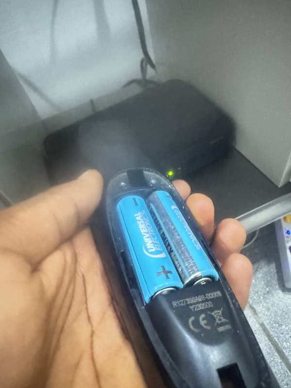 Open DStv remote battery compartment showing the contacts and model number label