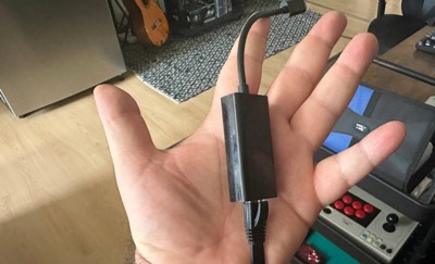 Close-up of a person’s hand holding an Ethernet cable and adapter for a stable wired internet connection