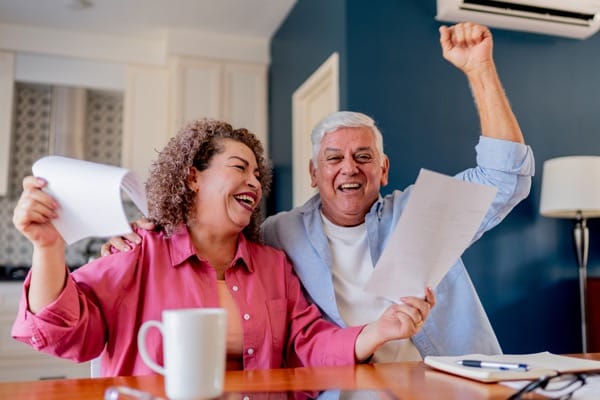 Happy couple celebrating good news while holding documents and papers at home