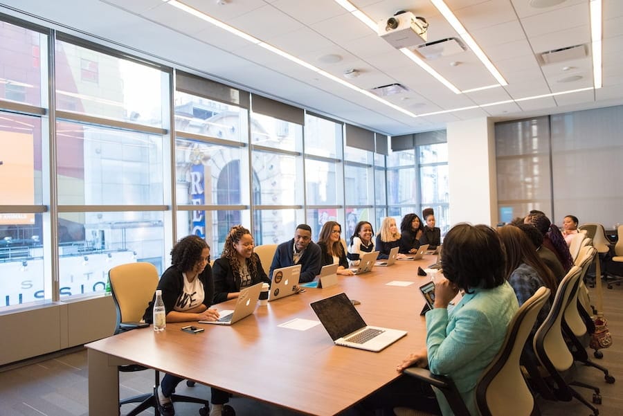 Large group of professionals working on laptops in a modern conference room during a business meeting
